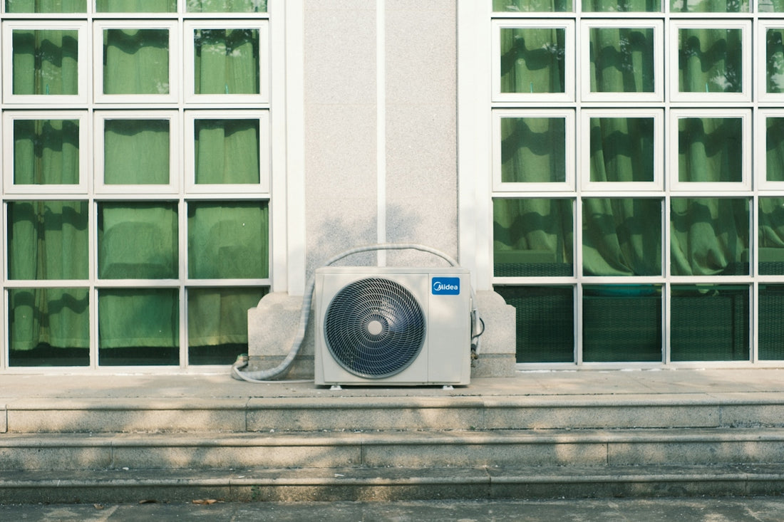 Air conditioner unit below large windows with green curtains