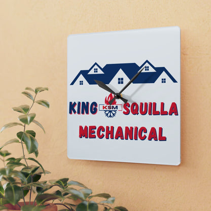 Wall clock with 'King Squilla Mechanical' logo on a beige wall with a plant in the foreground